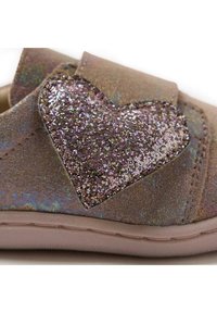 Scarpa in tessuto marrone glitterato con un grande accento a forma di cuore scintillante in tonalità iridescenti. Chiusura con strap in velcro. Suola morbida.