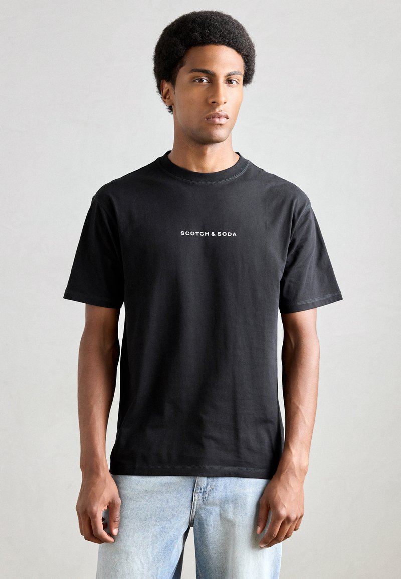 Black cotton t-shirt featuring a classic crew neck and short sleeves. 'Scotch & Soda' logo in white printed on the front.