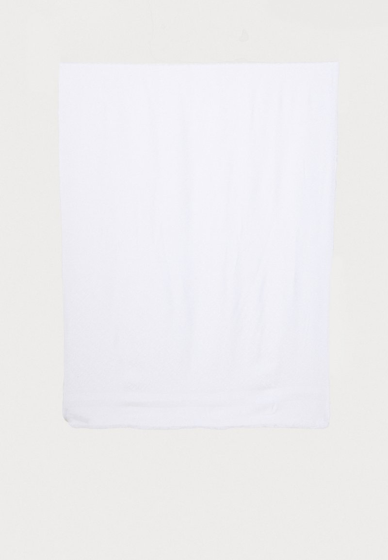 Serviette blanche en coton doux et texturé. Forme carrée avec des bords soigneusement ourlés, montrant des plis et des creux subtils.