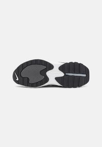Outsole Nike tenisic v črni in beli barvi. Ponuja teksturirane vzorce in utore za oprijem, z vidnim logotipom Nike na peti.