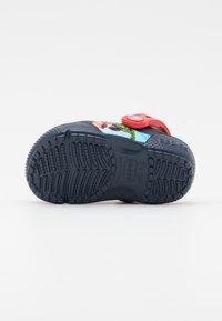 Chaussure pour enfant bleu marine avec un design graphique coloré, semelle texturée et sangle rouge ajustable pour un maintien sécurisé.