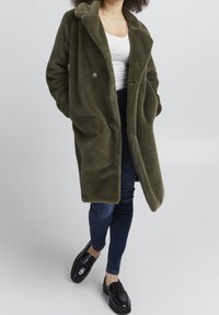 Olivgrön fleecemantel med kavajkrage och enkel knappstängning, med sidofickor och en mjuk, strukturerad yta.