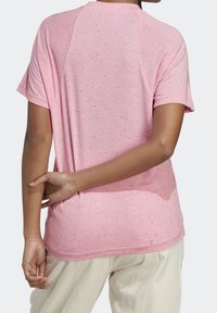 Rosa kortärmad t-shirt med en prickig textur, rundad halslinje och raglanärmar, med en avslappnad passform bak.