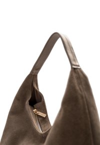 Bruine suède handtas met een gebogen vorm, voorzien van een ritsvak en een glad leren hengsel. Subtiele texturen en gouden hardwaredetails.