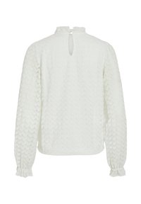 Blouse blanche texturée à manches longues, avec un dos en forme de trou de serrure et des poignets élastiques, confectionnée dans un tissu tricot léger.