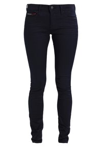 Jeans ajustados de denim azul oscuro con una textura suave. Presentan un cierre de botón en la parte delantera, cinco bolsillos y un pequeño detalle rojo en el bolsillo frontal.