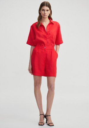 Conjunto de camisa de lino roja de manga corta y pantalones cortos a juego. Presenta un frente con botones, un bolsillo y cintura elástica. Textura suave y ligera.