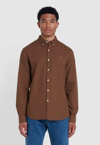 Bruine button-down shirt met witte knopen en een klein geel logo op de linkerkant van de borst. Lange mouwen en een klassiek kraagontwerp.