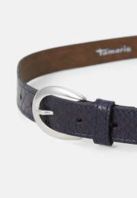 Ceinture en cuir texturé bleu marine avec une boucle en métal argenté en forme de D et des coutures contrastées. Dessous lisse avec le logo de la marque.