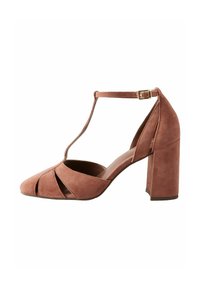 Pompe à talons hauts en daim rose avec un design à T, bout arrondi et découpes. Présente un talon épais et carré. Bride à la cheville ajustable.