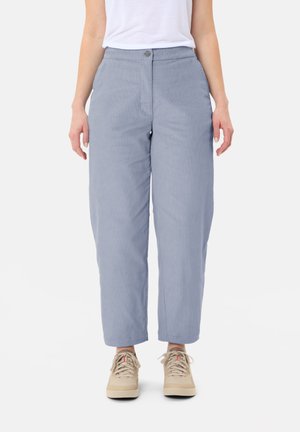 Lichtblauwe, wijde broekspijpen van gestructureerde stof, met voorzakken en een knoopsluiting. Gepaard met beige sneakers.