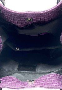 Wnętrze torby z fioletowego, plecionego materiału z zamykaną kieszenią, czarną podszewką i zapięciem na zatrzask. Posiada płaskie dno dla stabilności.