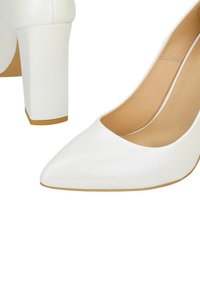 Chaussures à talons hauts blanches avec un bout pointu, texture en cuir lisse et un talon carré chunky. L'intérieur est doublé en tan.