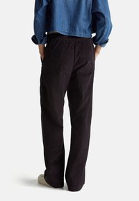 Černé kordové kalhoty volného střihu s elastickým pasem a bočními kapsami, doplněné džínovou bundou. Viditelná texturovaná látka.
