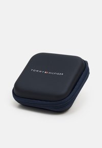 Marine harde koffer met een glad oppervlak en een ritssluiting; beschikt over het "TOMMY HILFIGER" logo in witte en rode letters op de bovenkant.