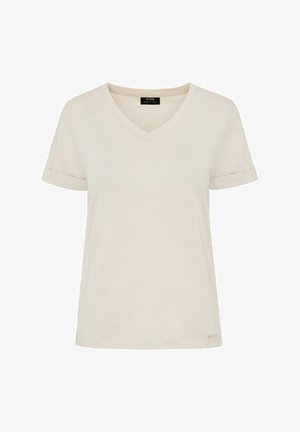 Kremowa koszulka z dekoltem w kształcie litery V i krótkimi, podwiniętymi rękawami, wykonana z miękkiego materiału. Posiada małą metkę marki na dolnej prawej stronie.