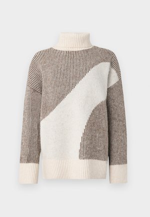 Paksu neulepusero, jossa on korkea kaulus, ruskeita ja kermaan värisiä raitoja, pehmeä rakenne ja suuri kerma valkoinen graafinen kuvio yhdellä sivulla.