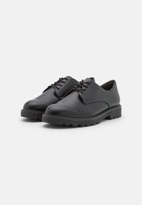 Chaussures en cuir noir à lacets avec un bout arrondi, un design minimaliste, une semelle texturée et une semelle extérieure en caoutchouc noir robuste.
