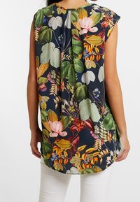 Blusa floreale con sfondo blu scuro, maniche corte e orlo arrotondato. Foglie verdi di varie tonalità e fiori colorati decorano il tessuto.