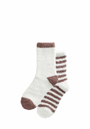 Ett par fluffiga vita strumpor; en helt vit med brun tå och mud, den andra vit med bruna ränder, häl och tå.