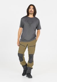 T-shirt gris léger avec un graphique de cerf géométrique, associé à un pantalon cargo vert olive et gris foncé avec poches zippées et genoux renforcés.