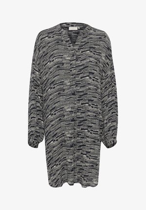 Koszula na krótki rękaw, zapinana na guziki, w granatowym kolorze z białym abstrakcyjnym wzorem. Miękka, lekka tkanina o luźnym kroju i plisowanym wzorze.