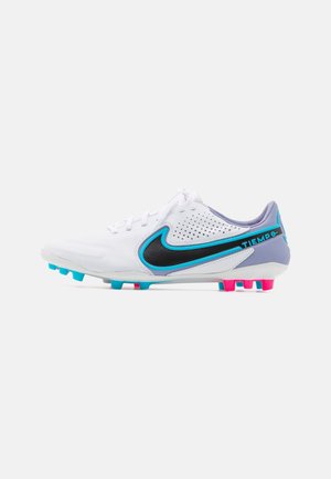 White Nike Tiempo soccer cleat with black and blue swoosh, perforated upper, and pink and blue studs on the sole.