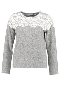 Pull gris à manches longues avec une superposition de dentelle florale blanche sur la poitrine et les épaules, col rond, et une étiquette de taille moyenne.