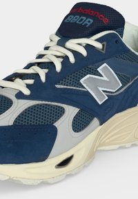 Μπλε και γκρι αθλητικό παπούτσι New Balance 990v3 με λευκά κορδόνια, πλεκτές επιφάνειες και μπεζ μαλακή σόλα.