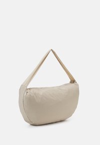 Borsa a spalla beige con una forma morbida e arrotondata, realizzata in tessuto leggero. Presenta una sola tracolla larga per un trasporto facile.