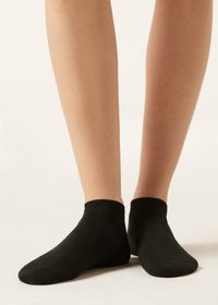 Calcetines negros de tobillo hechos de tela suave y elástica con una textura lisa. Presenta un puño acanalado y un diseño de punta sin costuras.