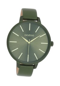 Montre verte avec une finition mate, au design minimaliste, dotée d'index horaires blancs contrastants et d'un bracelet en cuir vert lisse. Logo de la marque "OOZOO" affiché.