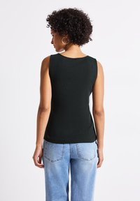 Czarny prążkowany top na ramiączkach z okrągłym dekoltem, bez rękawów i dopasowanym krojem, w połączeniu z jasnoniebieskimi spodniami o szerokich nogawkach.