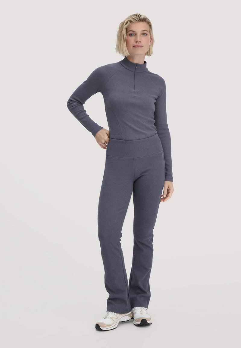 Aangesloten twee-delig workoutset in donkergrijze stof. Lange mouwen top met rits en flared broek met een brede elastische tailleband.