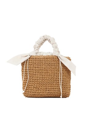 Borsa in paglia intrecciata con manico in tessuto beige chiaro e due fiocchi decorativi. Forma rettangolare, superficie testurizzata, colore naturale marrone chiaro.