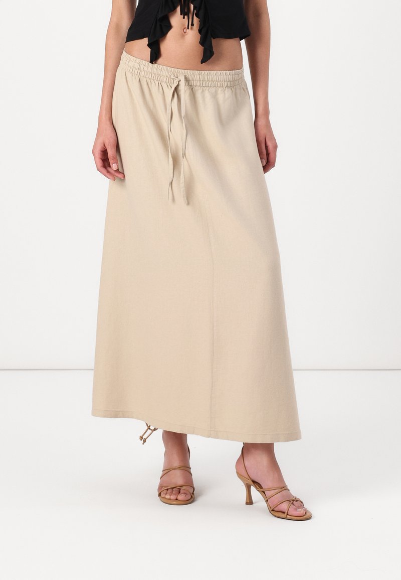 Fustă bej, lungime până la glezne, cu talie elastică și șnur. Fabricată dintr-un material ușor, prezintă o textură netedă și un design minimalist.