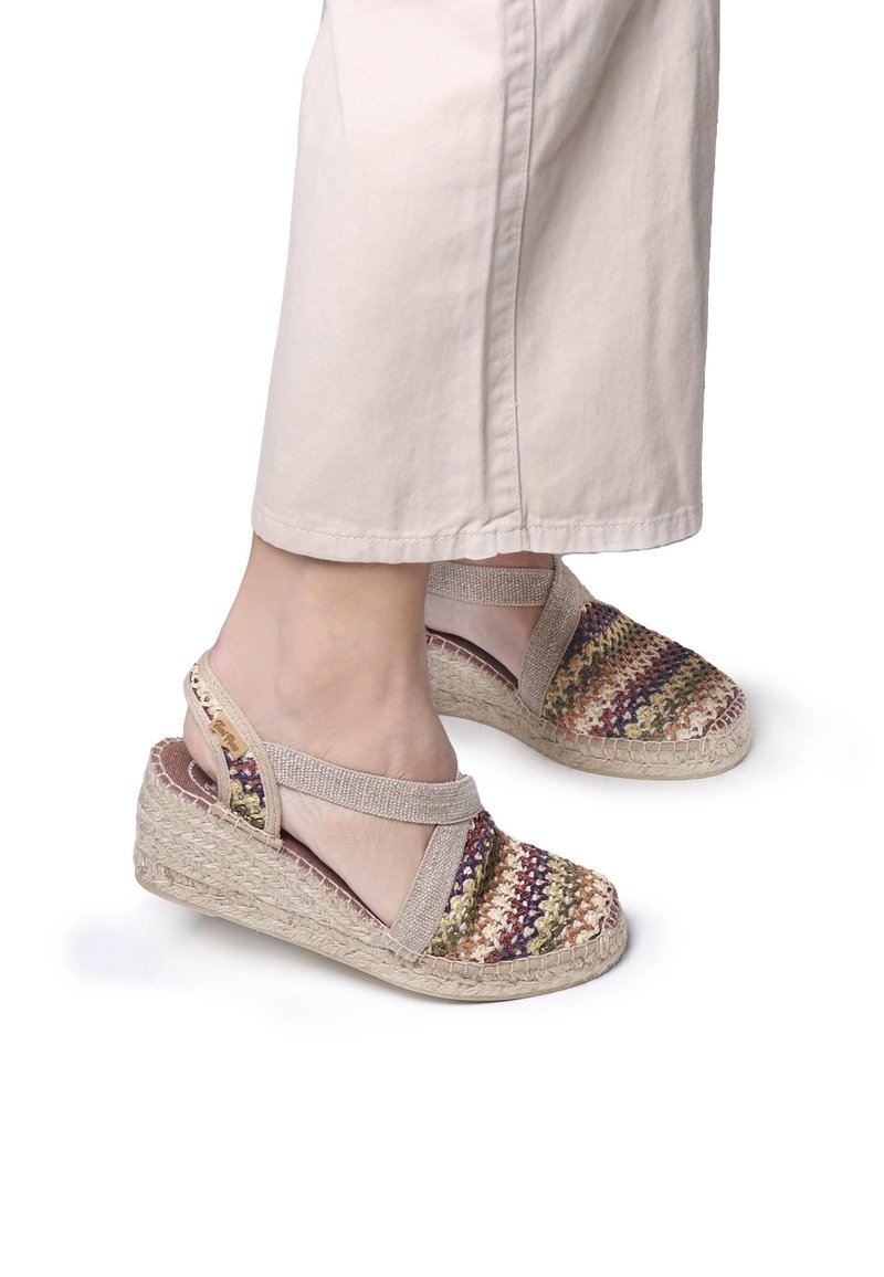 Sandali con zeppa realizzati in tessuto multicolore intrecciato e materiali naturali, dotati di una fascia elastica e di una suola avvolta in juta.