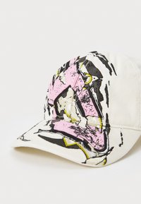 Casquette en toile de couleur écru avec des graphismes abstraits en noir, rose et jaune. Visière courbée, sangle ajustable à l'arrière, surface texturée.