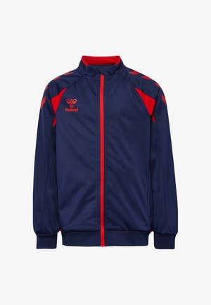 Marineblå sportjakke med rød lynlås, røde skulderstriber og en rød hummel-logo på venstre bryst.