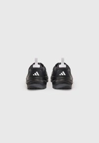 Chaussures de sport noires avec une tige texturée, détails du logo blancs, col rembourré et semelle en caoutchouc ; équipées de languettes de tirage au niveau du talon.