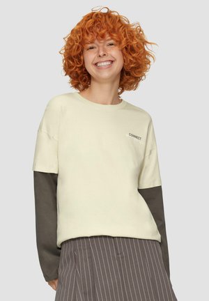Licht crème sweatshirt met donkergrijze lange mouwen. Bevat "CONNECT" tekst, ronde halslijn en een ontspannen pasvorm. Verticale gestreepte rok.