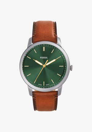 Montre ronde en argent avec cadran vert, aiguilles et repères dorés, bracelet en cuir marron, et logo Fossil à la position 12 heures.