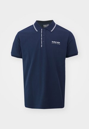 Polo majica v mornarsko modri barvi z belimi detajli na ovratniku in rokavih. Na sprednji strani je v beli barvi prikazan logotip "RedBull Racing". Narejena je iz udobnega bombažnega materiala.
