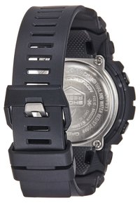 Montre numérique noire avec un bracelet en caoutchouc texturé, dotée de grandes découpes rectangulaires et d'un dos en acier inoxydable avec des détails en motif circulaire.
