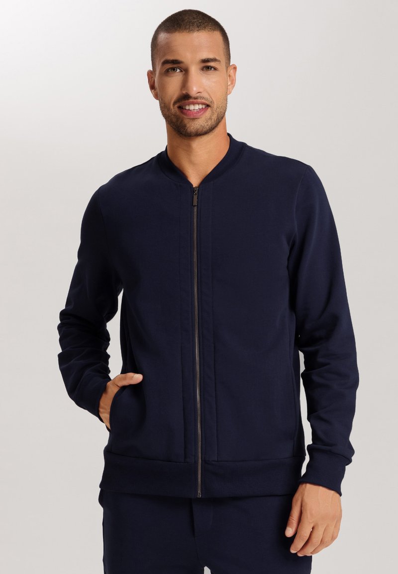 Sudadera con cremallera en color marino, hecha de una tela suave, con cuello alzado, mangas largas y bolsillos laterales. Diseño minimalista sin patrones.