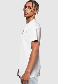 White cotton short-sleeve T-shirt with a crew neck. Features a graphic design on the chest and a relaxed fit. Smooth texture, casual style.
