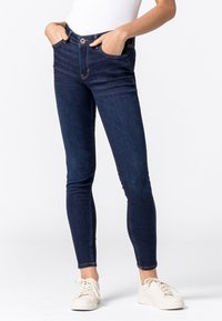 Dark blue skinny jeans with a high waist, front pockets, and a button closure. Features a smooth denim texture and slight fading.