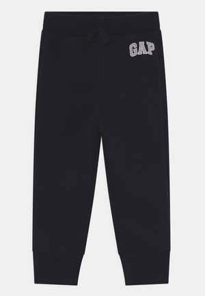 Pantalon de survêtement pour enfants bleu marine avec chevilles côtelées, taille élastique, cordon de serrage et logo blanc GAP sur la hanche gauche.