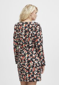 Robe noire avec un motif floral coloré en rouge, vert et blanc. Manches longues et design ajusté avec une taille cintrée.