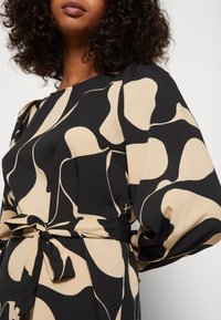 Vestido preto e bege com padrão, mangas longas e volumosas, cintura com cinto e textura suave.
